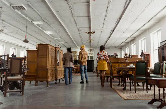 Shoppers browsing wooden furniture in a secondhand store