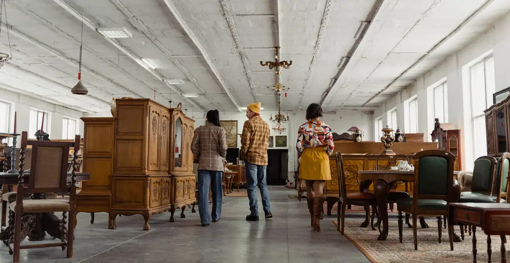 Shoppers browsing wooden furniture in a large secondhand store